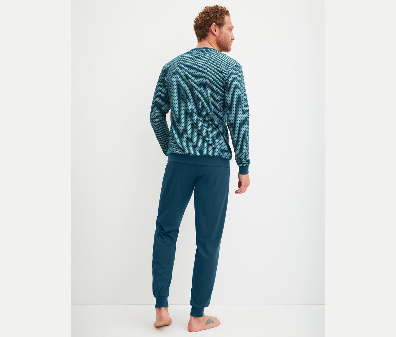 Mann von hinten in blauem Pyjama mit Muster.