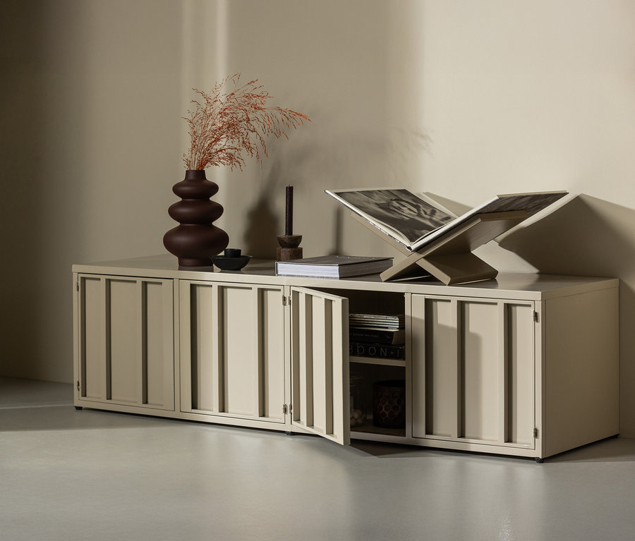 Sandfarbener WOOOD Metall-TV-Schrank »Level« mit Dekorationen steht an einer Wand, eine Tür ist geöffnet.