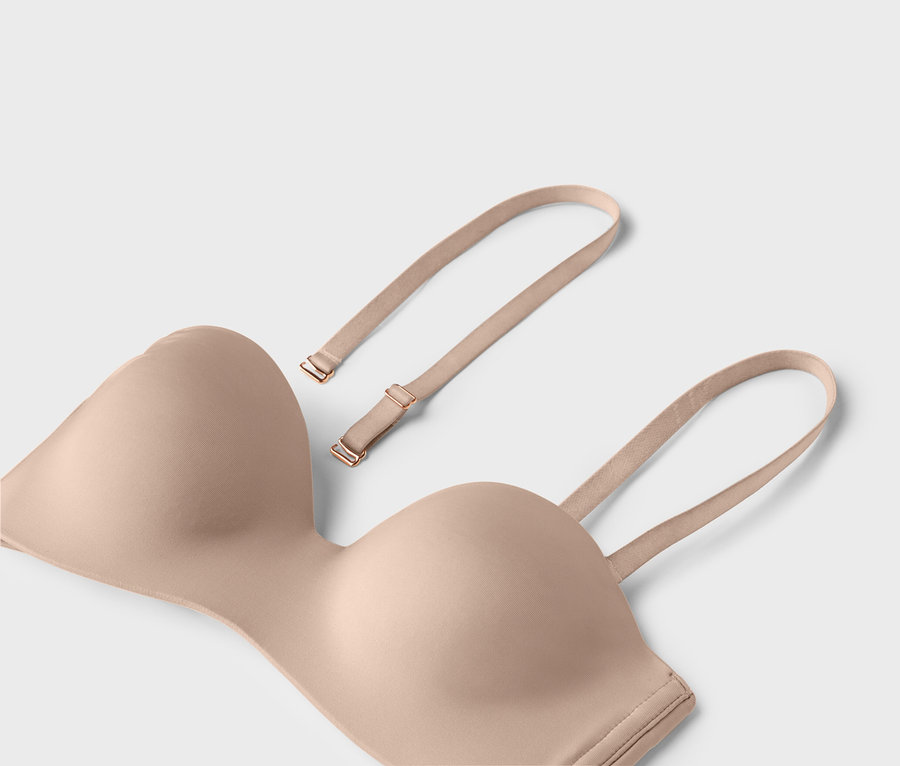 Ein hautfarbener trägerloser BH mit abnehmbaren Trägern liegt auf einem hellen Hintergrund.