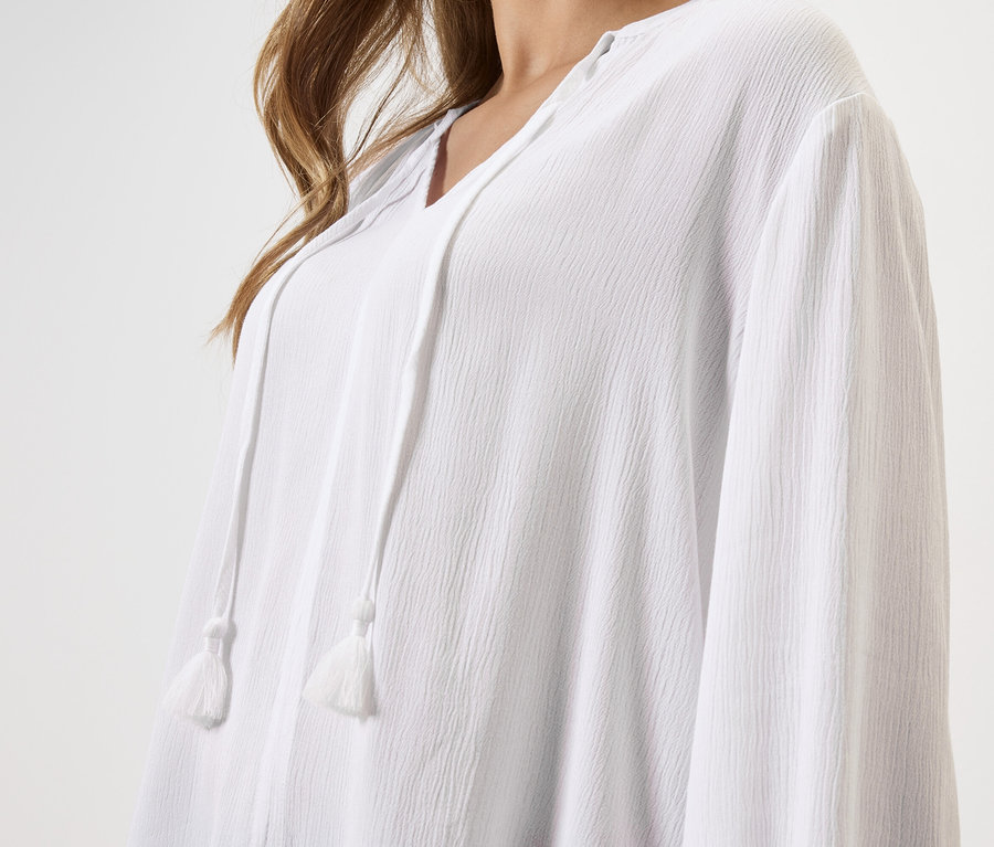 Nahaufnahme einer Frau, die eine weiße Bluse mit Kordelzug trägt.