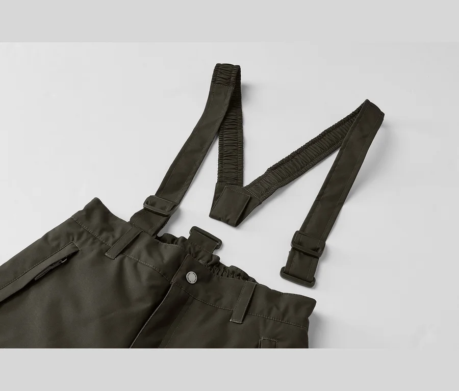 Dunkelgrüne Hose mit Hosenträgern, die hinten elastische Riemen und Schnallen haben, flach auf weißem Hintergrund liegend.