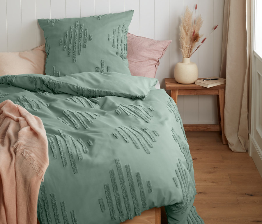 Grüne Struktur-Bettwäsche Normalgröße liegt auf einem Bett neben einer beige Decke.