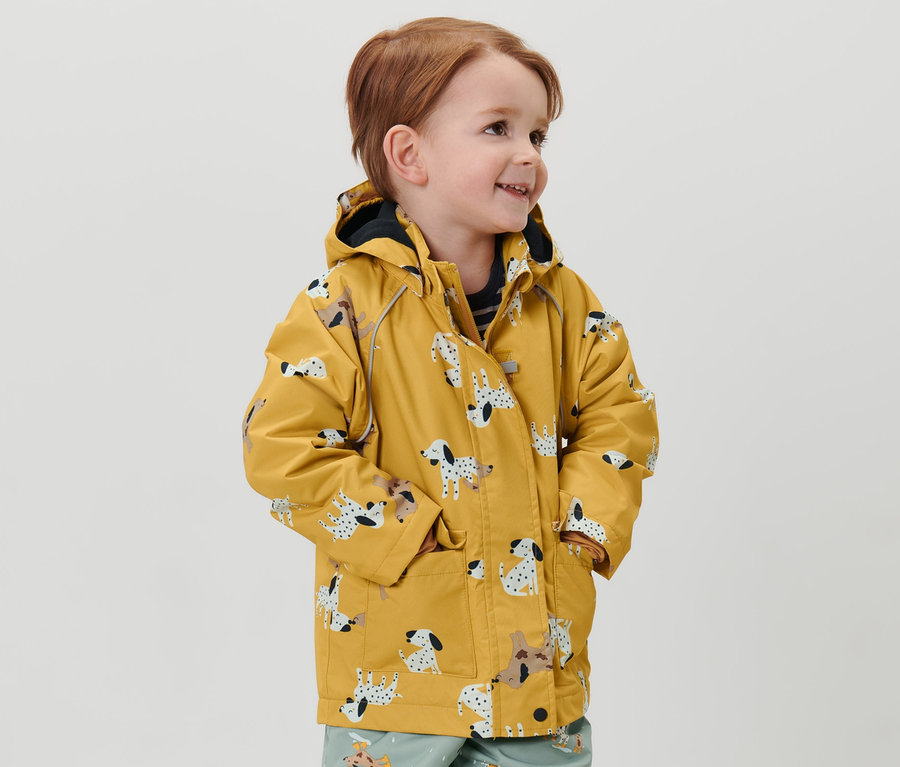 Junge trägt eine Kinder-Thermo-Regenjacke mit Dalmatiner-Muster und bedruckte Hose.