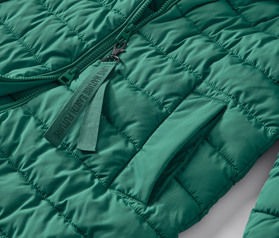Detailaufnahme eines grünen Steppmantels mit Kapuze.