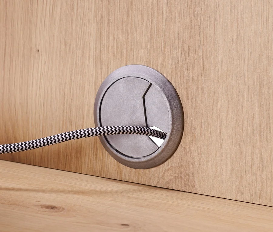 Detail eines Sideboards mit Schubladen und Tür, Kabel durch eine Öffnung geführt.