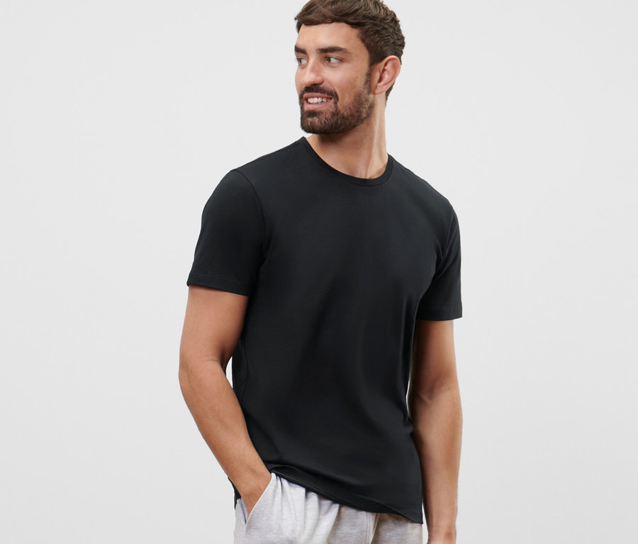 Mann mit Bart trägt ein schwarzes 2 T-Shirts mit Rundhalsausschnitt und graue Shorts.