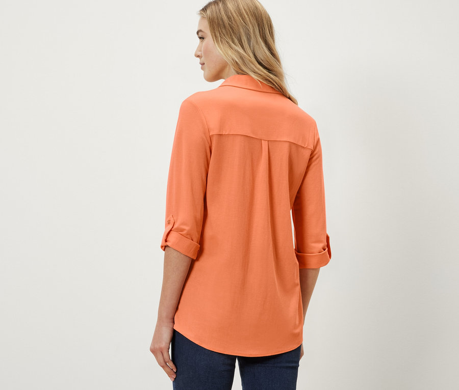 Frau trägt eine Piqué-Jerseybluse in Peach.