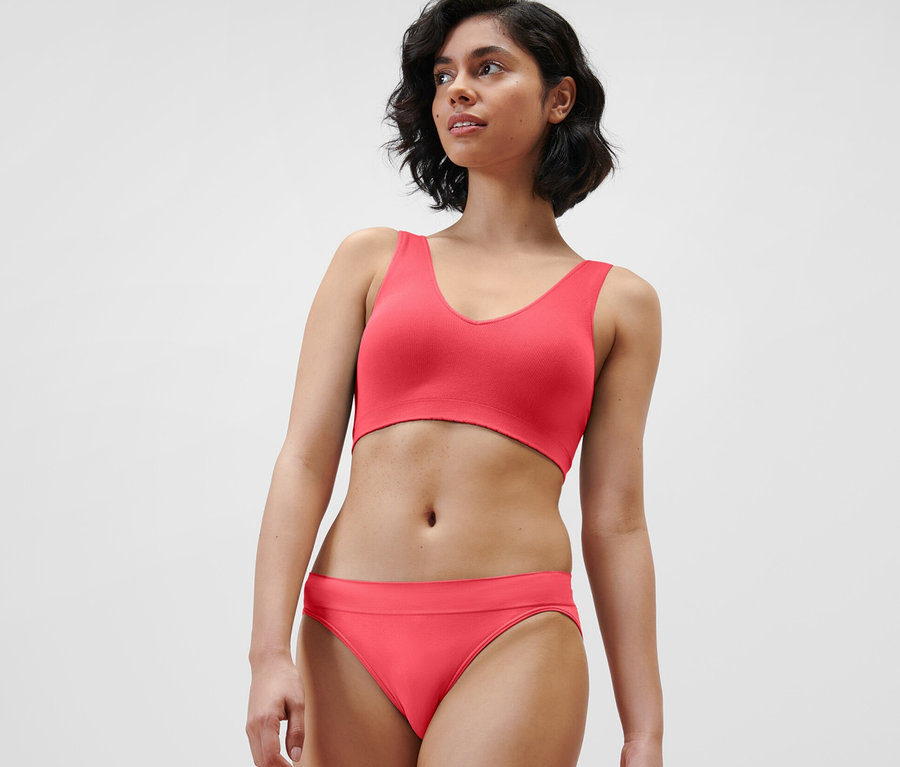 Frau trägt rotes Seamless-Bustier und Unterhose.