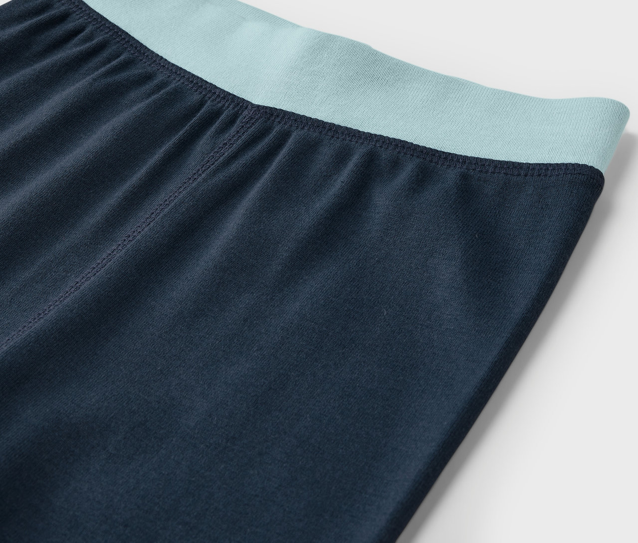 Detailaufnahme von marineblauen Leggings mit mintgrünem Bund.