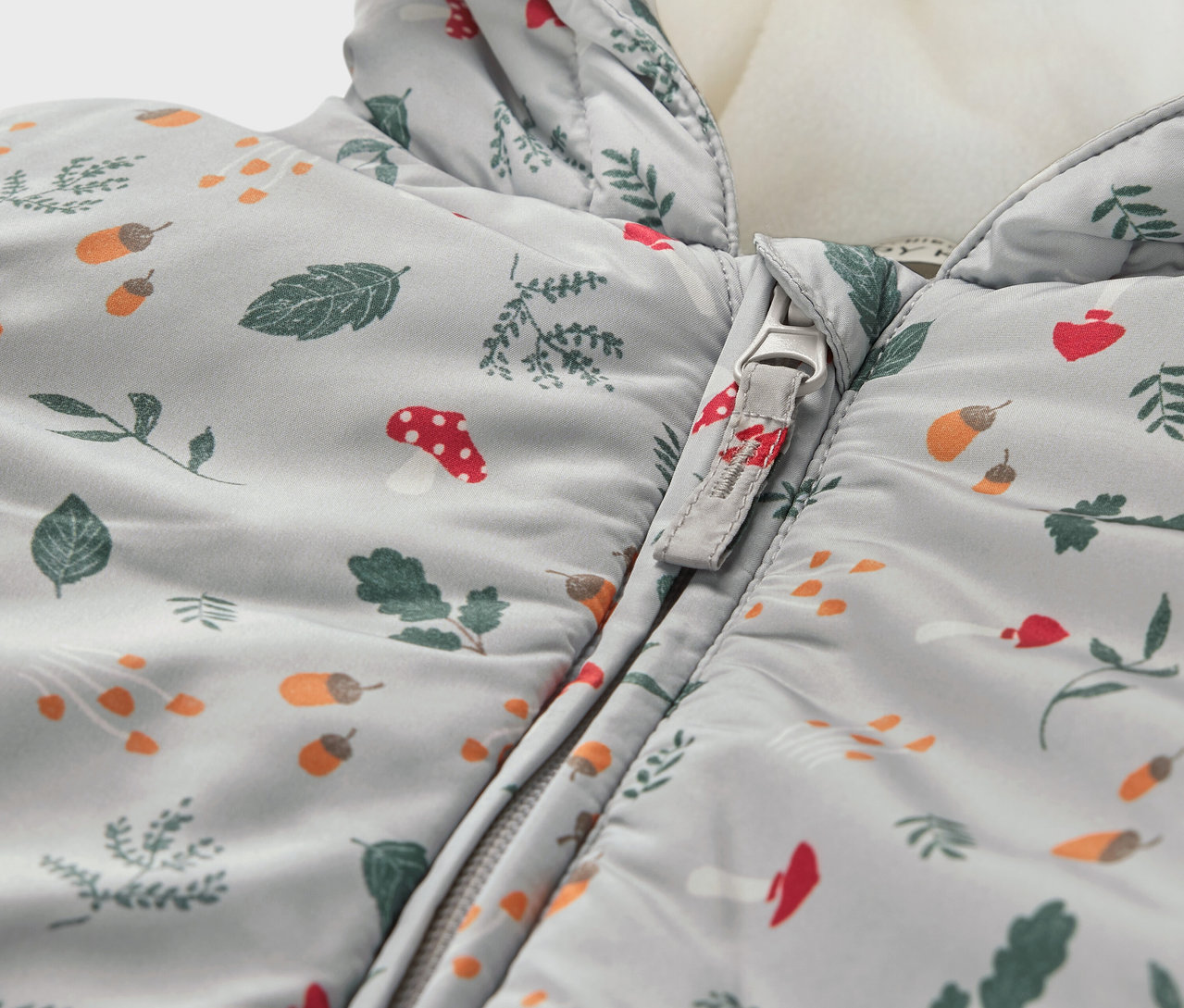 Detailansicht von Baby-Winteroverall mit Blätter-, Pilz- und Eichelmuster.