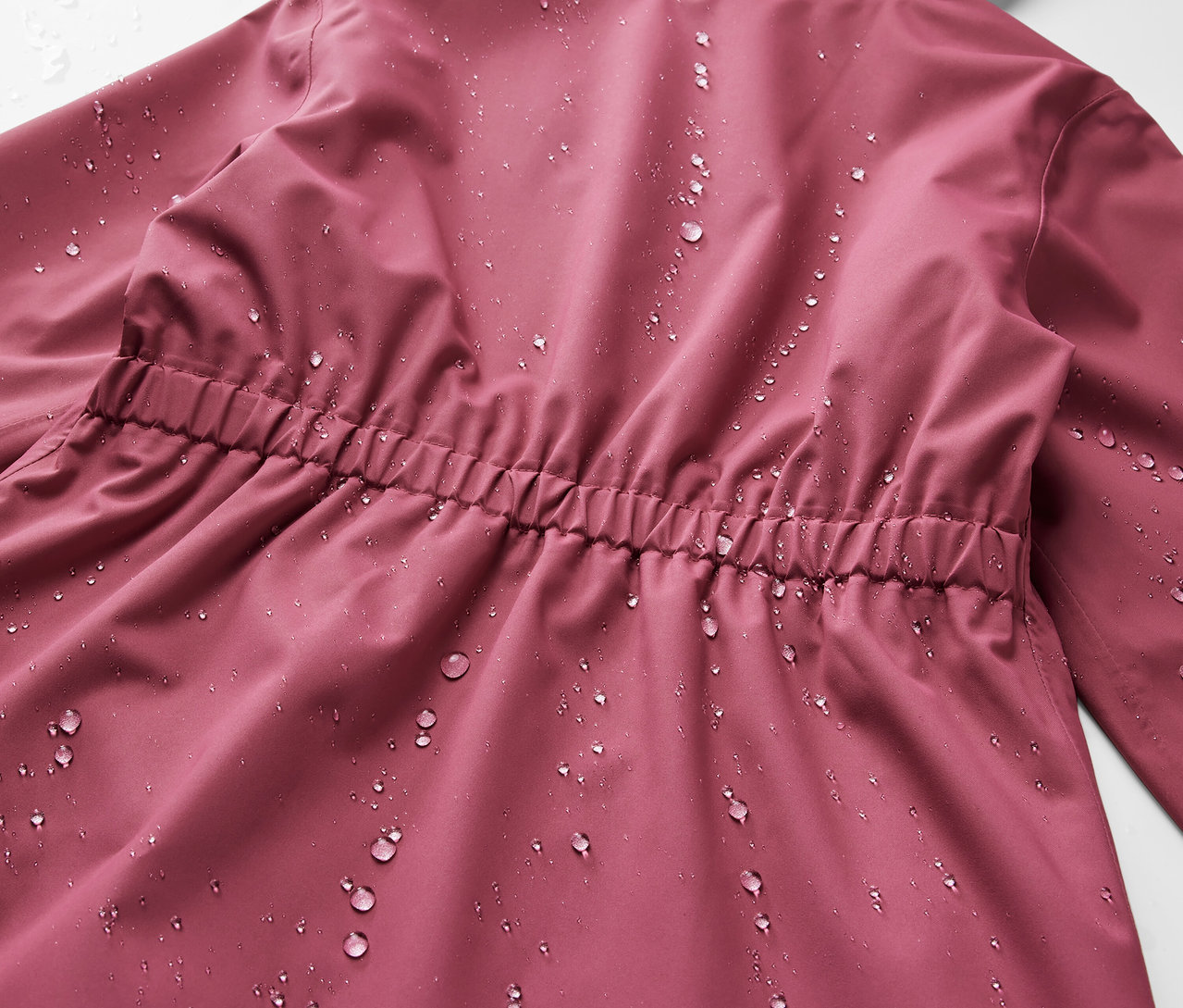 Nahaufnahme der Rückseite eines Kinder-Regenparkas mit Wassertropfen.