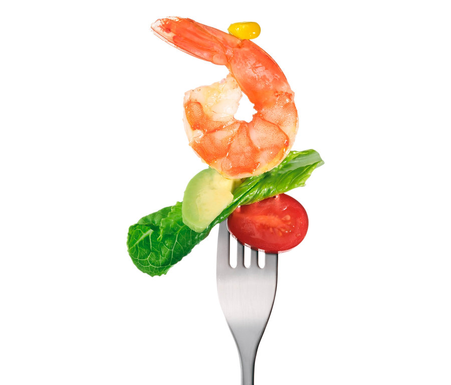 Garnele, Salatblatt, Avocado und Tomate auf einer Gabel.