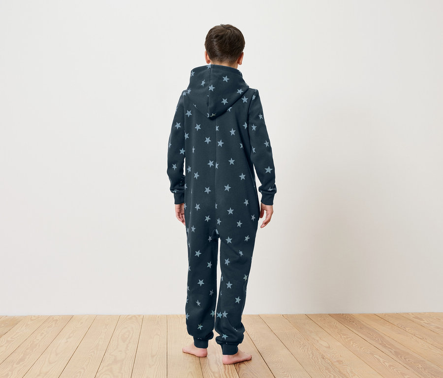 Ein Kind steht mit dem Rücken zur Kamera und trägt einen dunkelblauen Sternen-Overall mit Kapuze.