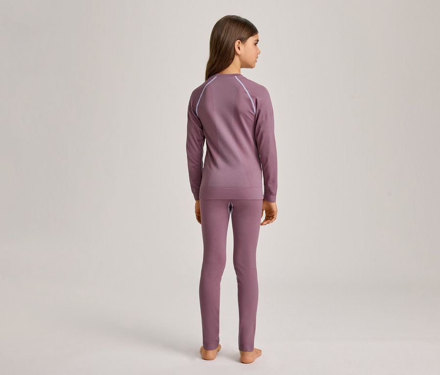 Mädchen von hinten, das ein langärmeliges, lilafarbenes Oberteil mit Muster und passende Leggings trägt. Sie steht barfuß vor einem hellen Hintergrund.