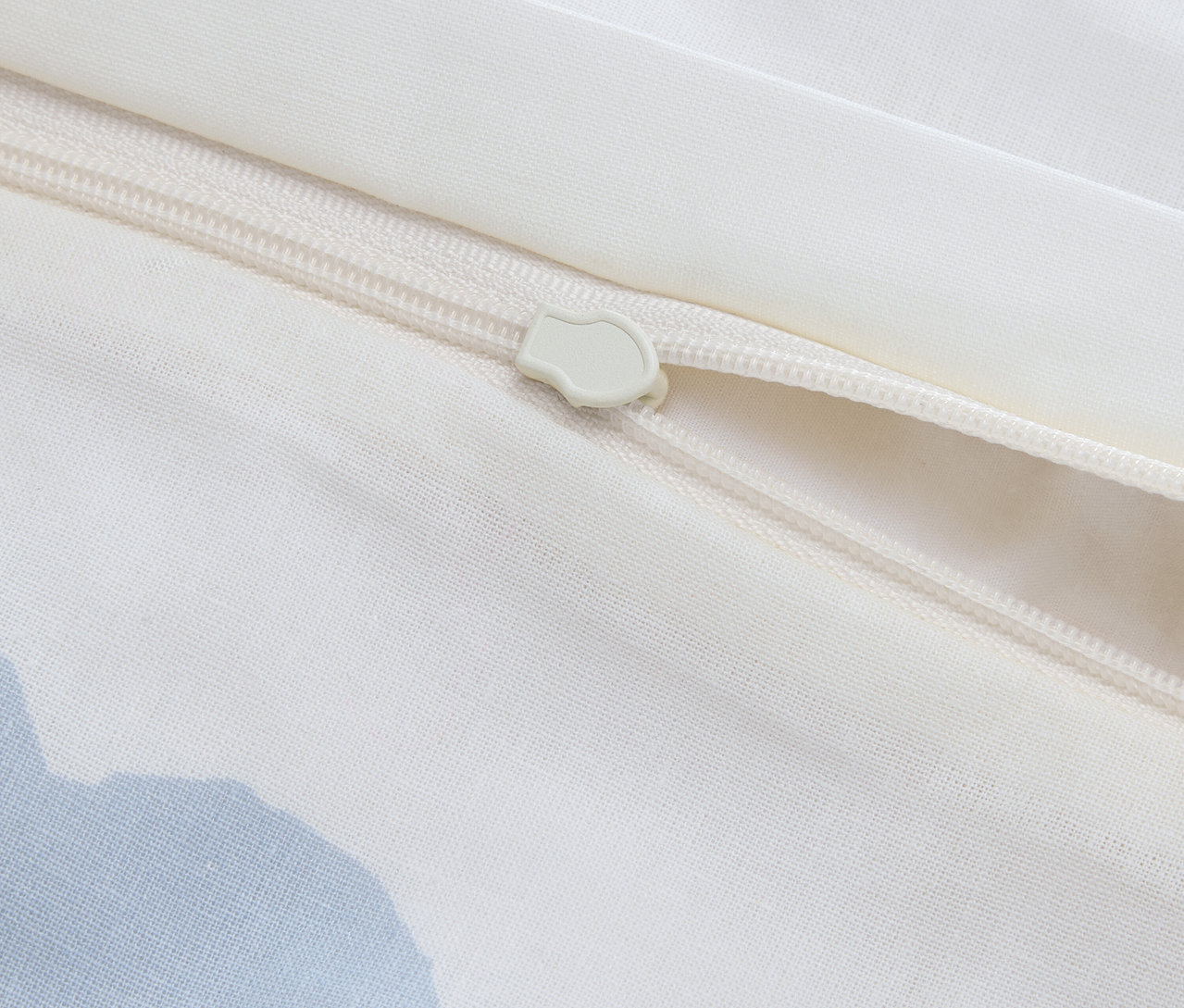 Nahaufnahme eines teilweise geöffneten Reißverschlusses auf einem weißen Stoffbezug.