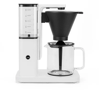 Weiße Wilfa Kaffeemaschine mit Wasserbehälter, schwarzem Filter und Glaskanne auf weißem Untergrund.