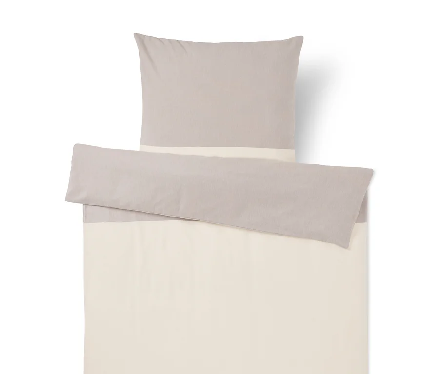 Bettwäsche-Set in Hellgrau und Creme. Ein Kissen und ein gefalteter Bettbezug mit Farbblock-Design.