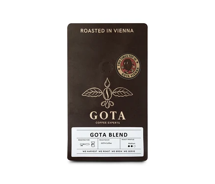 Dunkelbraune Packung Gota Coffee - Gota Blend Omni-Roast - 250 g Ganze Bohne, mit weißem Etikett, das "GOTA BLEND" und "ROAST PROFILE Medium" zeigt. Die Packung trägt auch den Text "ROASTED IN VIENNA" und ein "TWO TIMES TOP 10 GOTA VIENNA" Siegel.