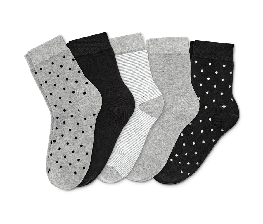 Fünf Paar Socken in verschiedenen Designs: grau mit schwarzen Punkten, schwarz, grau gestreift, grau und schwarz mit weißen Punkten.