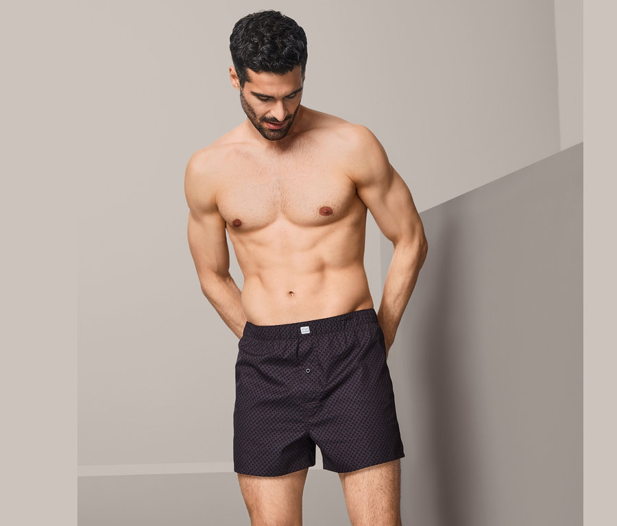 Mann posiert in 2 Webboxershorts.