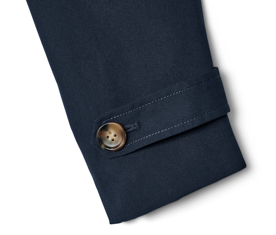 Detail vom Ärmel eines navy Trenchcoats mit braunem Knopf.