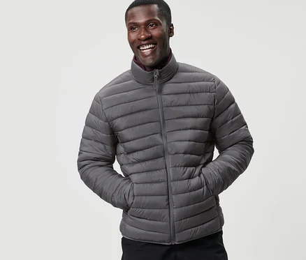 Ein lächelnder Mann posiert in einer verstaubaren Steppjacke.
