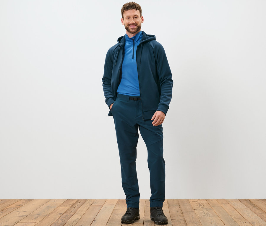 Mann steht und posiert in Thermohose mit Gürtel.
