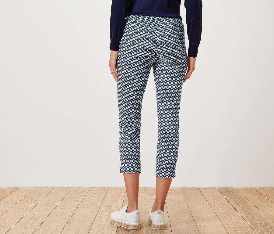 Rückansicht einer Frau, die eine bedruckte 7/8-Stretchhose und weiße Turnschuhe trägt.