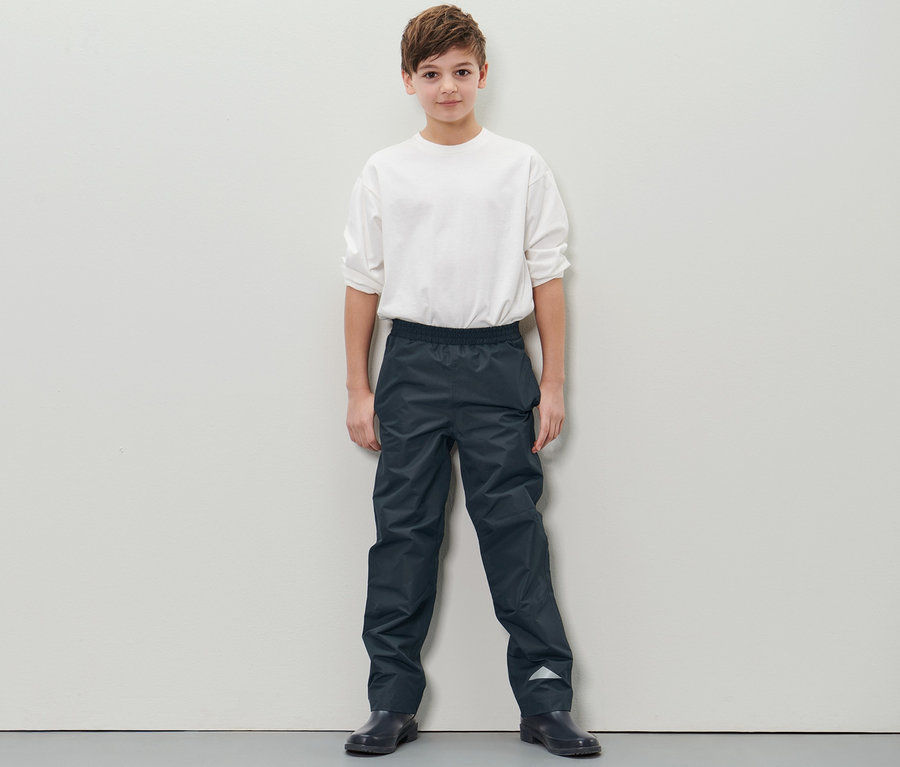 Junge steht und trägt eine Kinder-Regenhose.