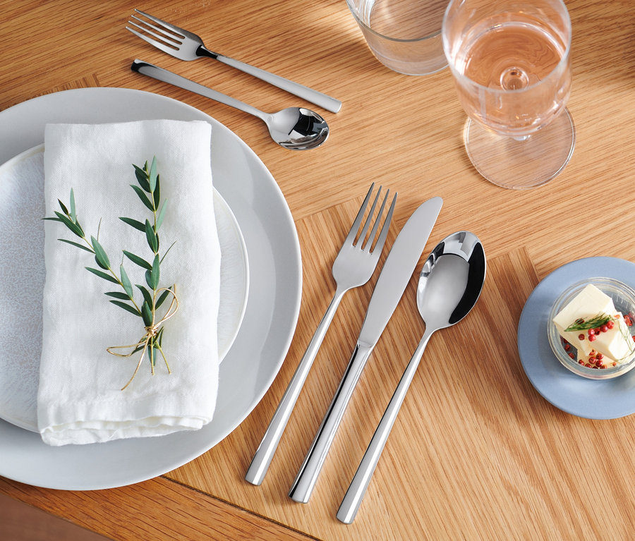 Besteck-Set, 20-teilig, edelstahlfarben auf einem Holztisch.