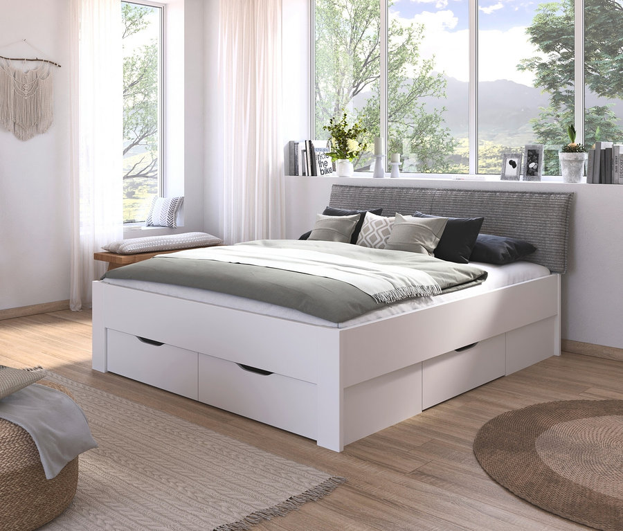 Schlafzimmer mit weißem Bett »Aditio Beds«, 180 cm mit Polsterkopfteil und Schubladen, neben Fenster mit Vorhängen.