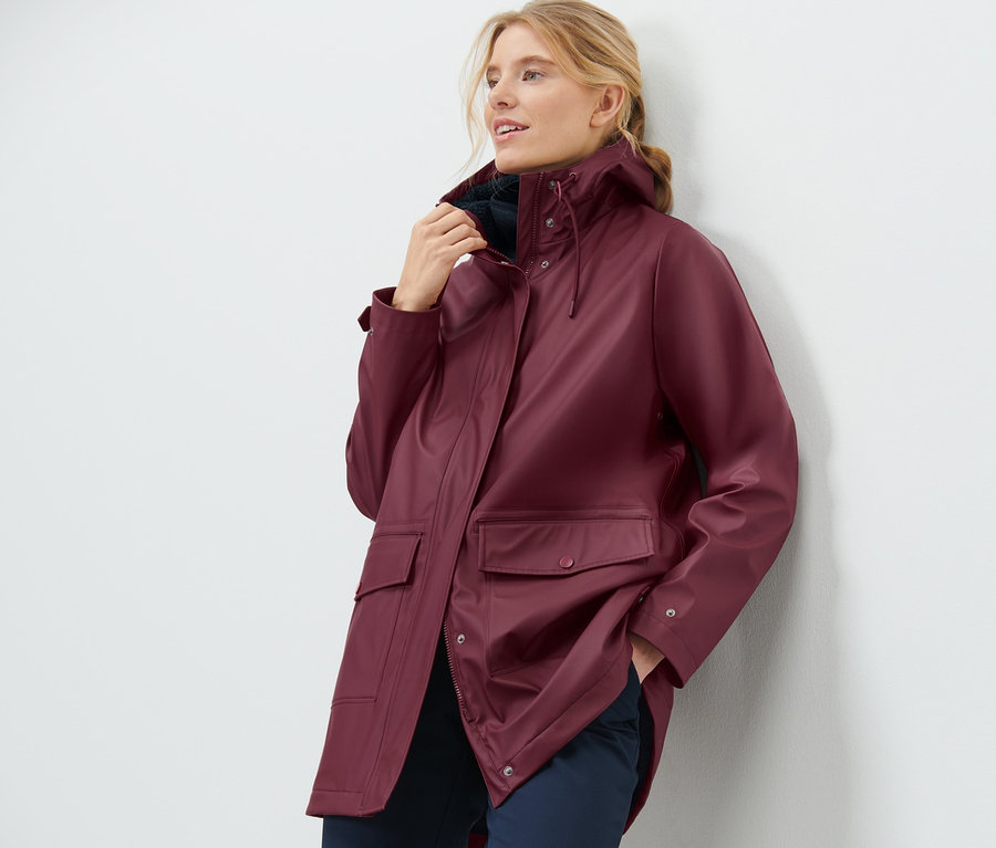 Frau posiert in einem bordeauxroten Teddy-Regenmantel.