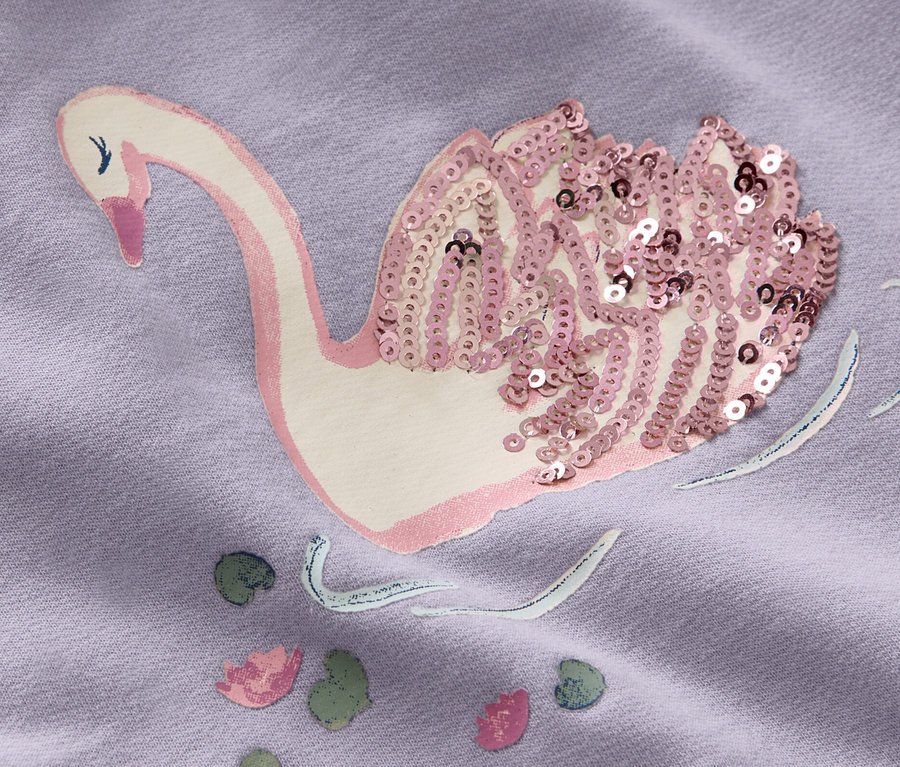 Detailaufnahme eines lila Kinder-Sweatkleids mit Schwan-Applikation, verziert mit Pailletten.