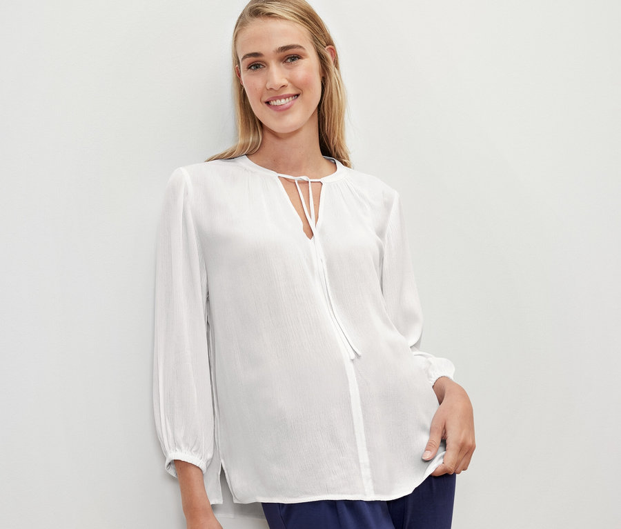Eine Frau trägt eine weiße Tunika-Bluse.