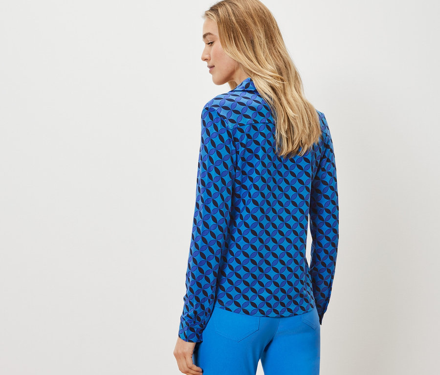 Frau trägt ein Blusenshirt mit Knopfleiste mit geometrischem Muster.