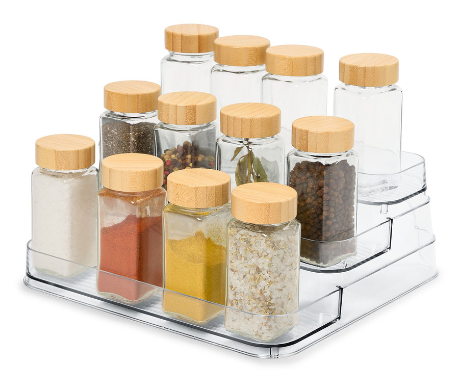 Auf einem durchsichtigen, dreistufigen Organizer befinden sich 12 Glas-Gewürzdosen mit Holzdeckeln.