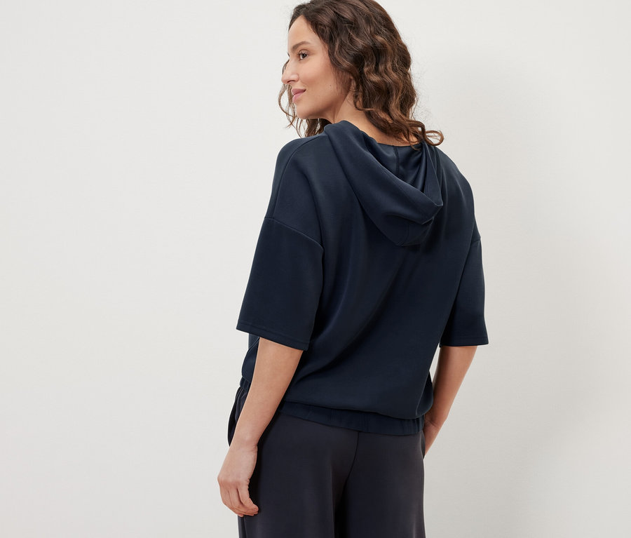 Frau trägt einen dunkelblauen Hoodie aus Modal-Mix und eine dunkelblaue Hose.