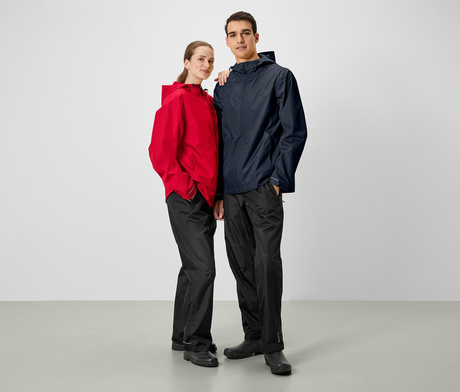 Ein Mann und eine Frau posieren nebeneinander. Beide tragen Regenjacken und schwarze Hosen.