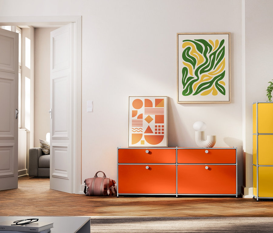 Wohnzimmer mit verschiedenfarbigen Metallkommoden, darunter ein orangefarbenes Sideboard »CN3« mit zwei Klappenfächern und zwei Schubladen, ein hellgraues Sideboard »CN3« mit zwei versetzbaren Klappenfächern, ein grünes Sideboard »CN3« mit einem Klappfach und eine gelbe Kommode »CN3« mit drei Klappenfächern.