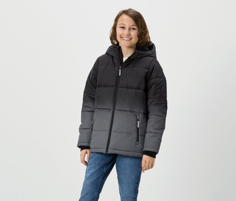 Mädchen posiert in grau-schwarzer Daunenjacke mit Kapuze und Jeans.