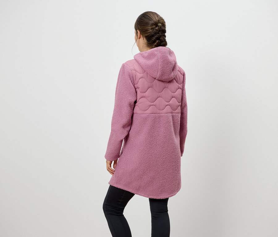 Frau mit dem Rücken zur Kamera trägt einen rosa Mantel mit Kapuze und schwarzen Leggings.