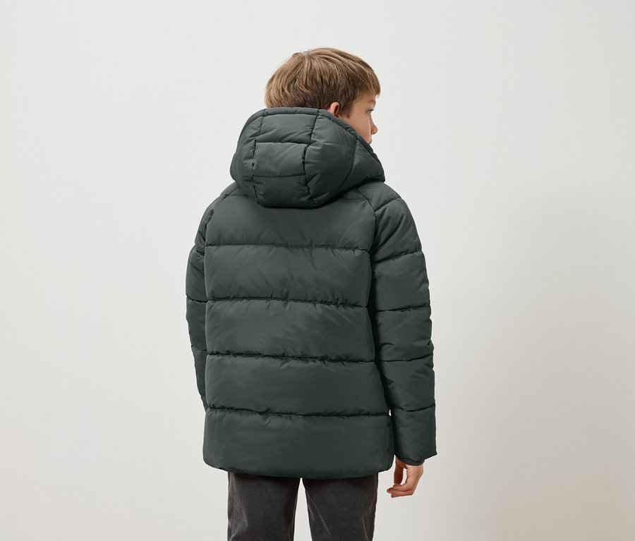 Junge mit dem Rücken zur Kamera trägt eine dunkelgrüne Daunenjacke mit Kapuze.