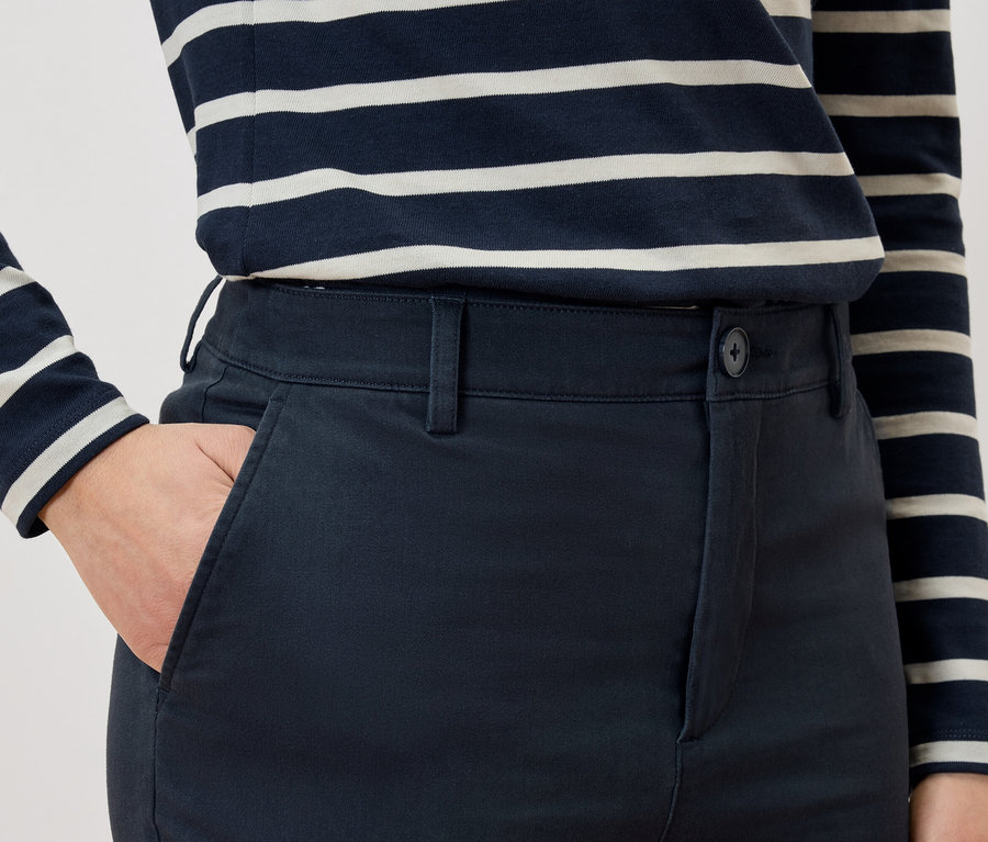 Detailaufnahme einer Person mit Hand in der Hosentasche und gestreiftem T-Shirt.