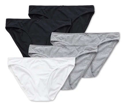 Fünf Baumwollslips in Weiß, Grau und Schwarz liegen übereinander.