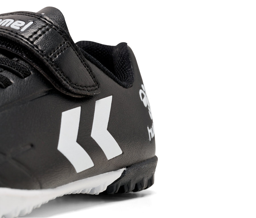 Detailansicht eines schwarzen Hummel-Schuhs mit weißem Logo und Klettverschluss.