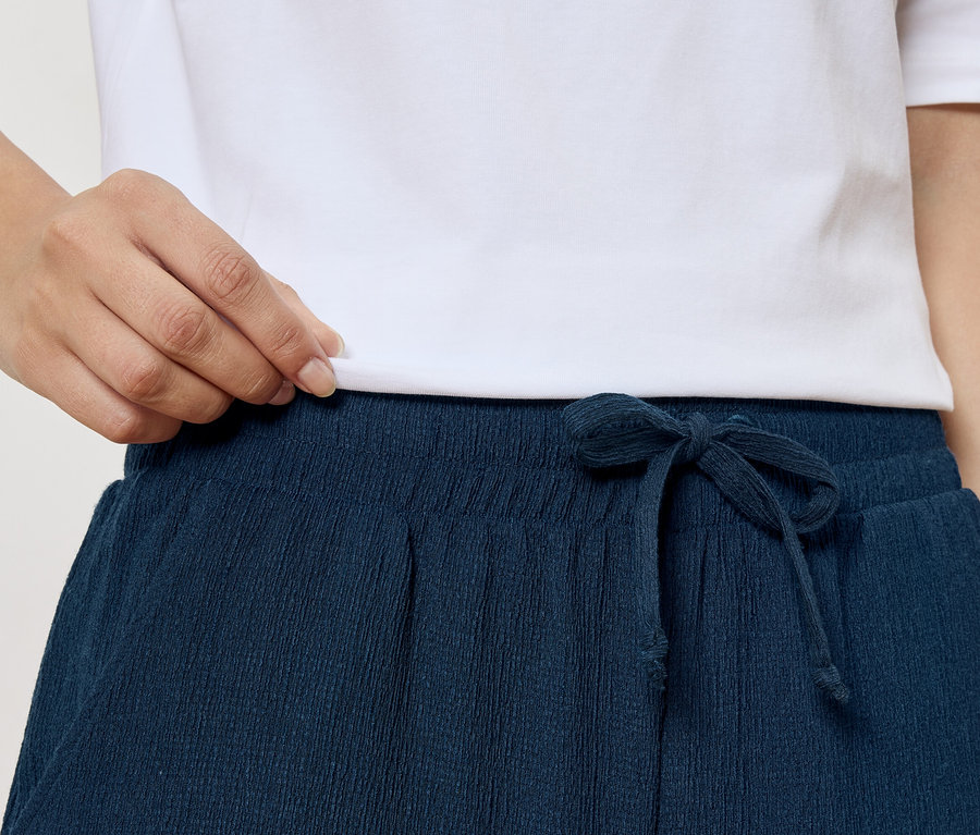Nahaufnahme einer Person in einem weißen T-Shirt und einer marineblauen Hose mit Kordelzug.