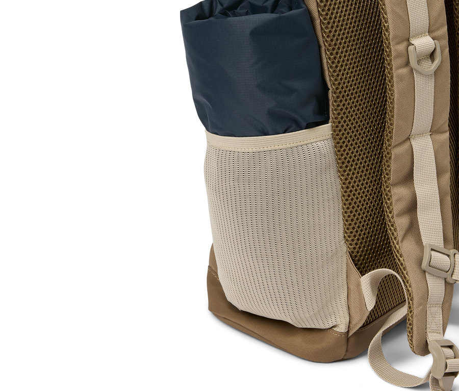Detailansicht eines beigen Rucksacks mit einer dunkelblauen Stoffrolle in einer Seitentasche aus Netzmaterial.