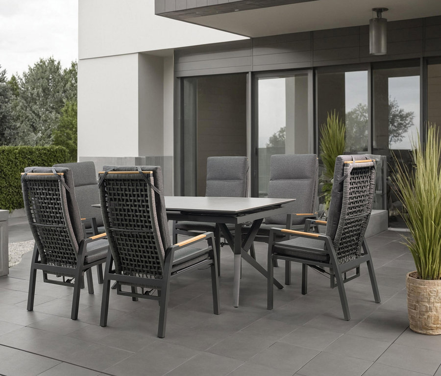 Sechs graue Stühle mit Armlehnen stehen um einen grauen Tisch auf einer Terrasse.