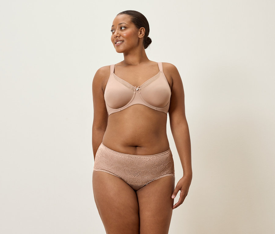 Frau trägt hautfarbenen BH und Spitzenhöschen.