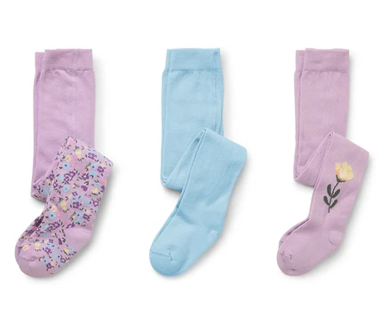 Drei Paar Kinderstrumpfhosen liegen auf einem weißen Hintergrund. Ein Paar ist hellblau, eines lila mit Blumenmuster und eines lila mit einer gelben Blume.